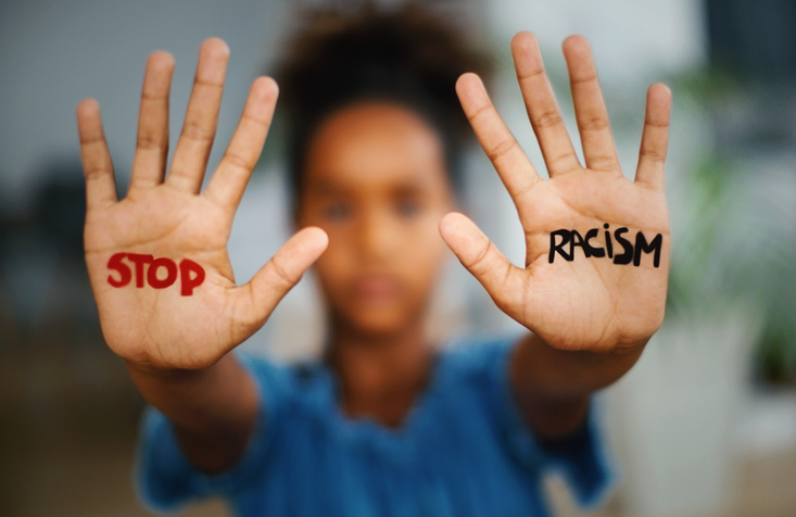 Black woman with palms facing camera saying "Stop Racism". Black Lives Matter