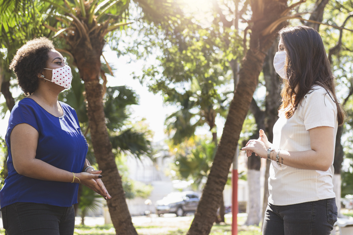 Two women chatting in park with masks on