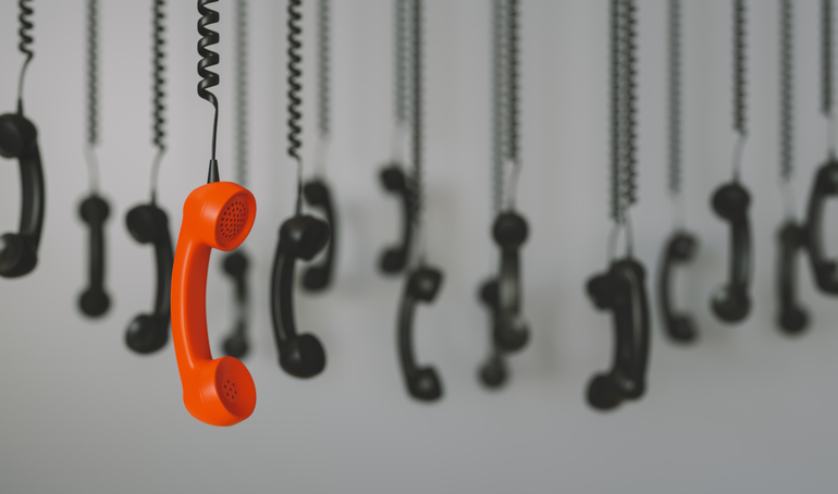 Phones hanging from their cords, one orange one stands out