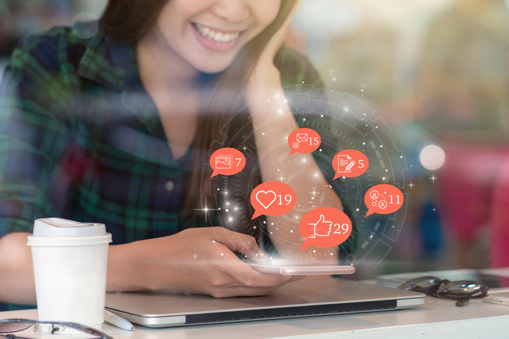 Woman looking at phone with social notification icons in the air