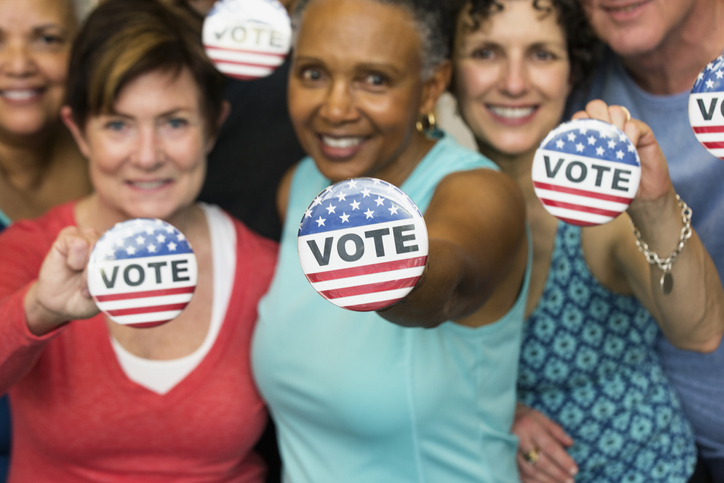 women holding vote buttons