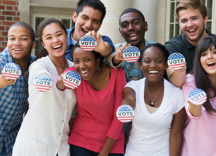 A group of people holding up voter stickers and smiling A group of people holding up voter stickers and smiling