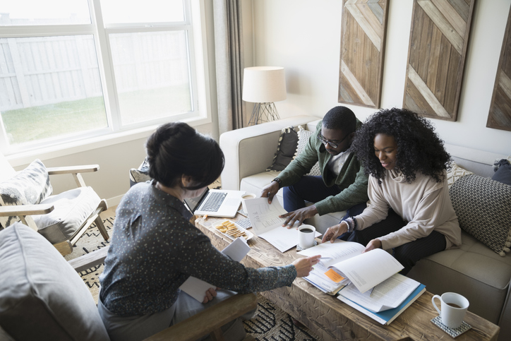 People meeting around a table piled with papers