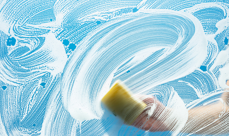Image of a soapy window with a person scrubbing it down. Image of a soapy window with a person scrubbing it down.