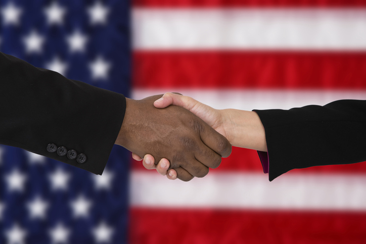 close up of two people shaking heads with american flag backdrop