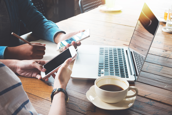 Two people looking at phones to plan their winning digital ad campaign. 