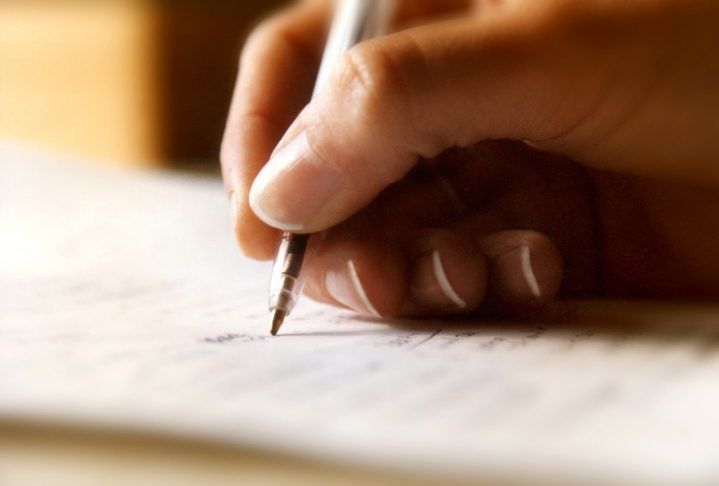 a hand writes in a notebook