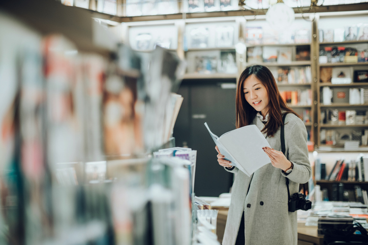 Professional female photographer reading books in book store for inspiration