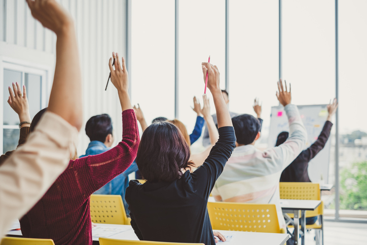 A group of people in a room raising their hands. 