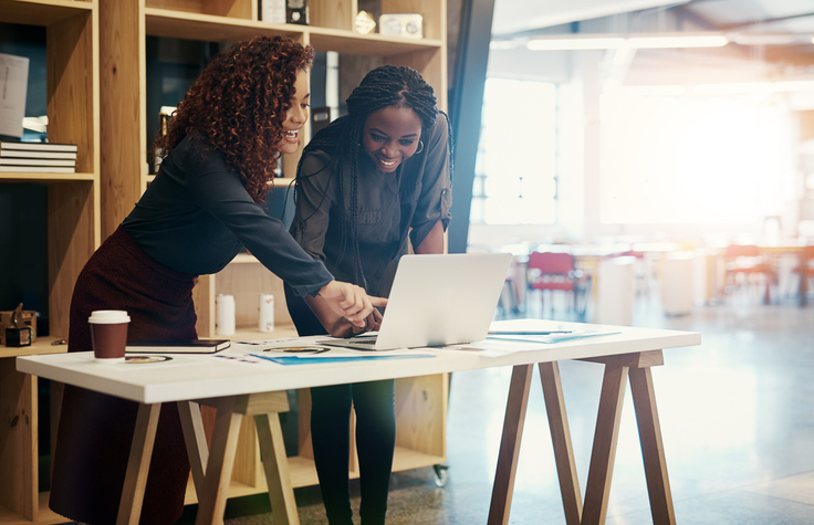 Two women looking at a laptop on a table advocacy website RFP