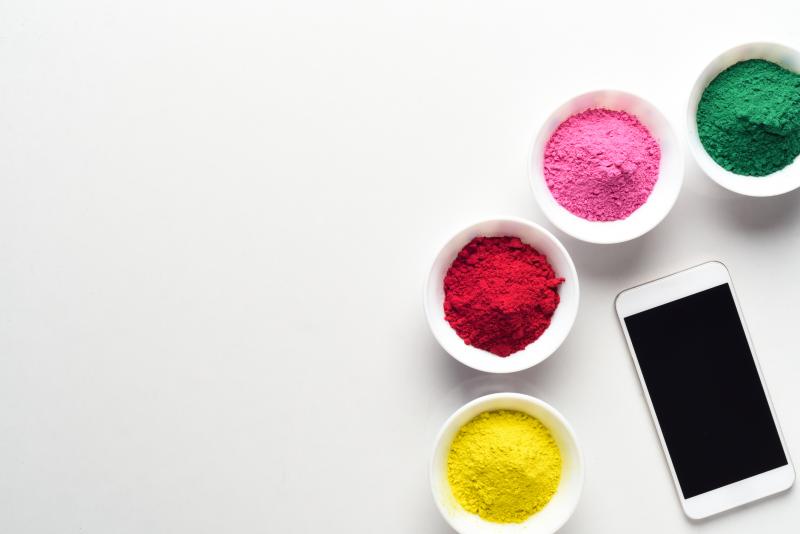 White iPhone surrounded by holi colors. iPhone surrounded by holi colored bowls to symbolize choices.