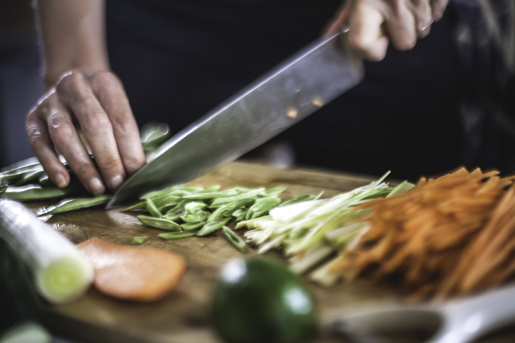 Chef holding a knife cutting spring onions