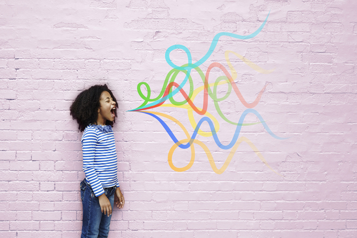 Girl in front of pink brick wall with colorful chalk lines drawn -storytelling for campaign communications. 