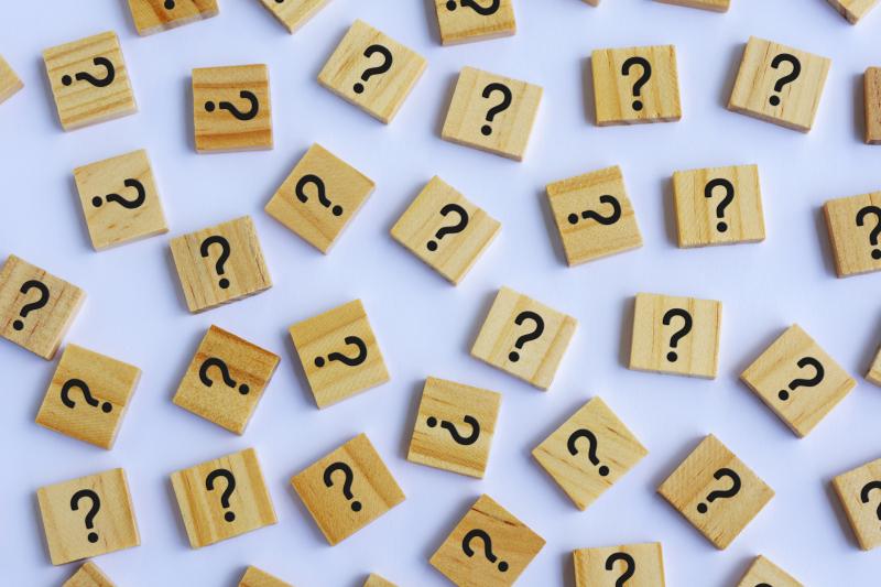 Black question marks on a scattered group of wooden tiles