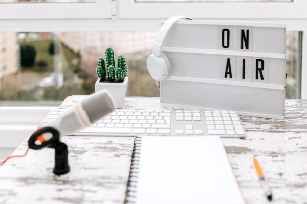 Headphones hanging on "on air" sign behind microphone