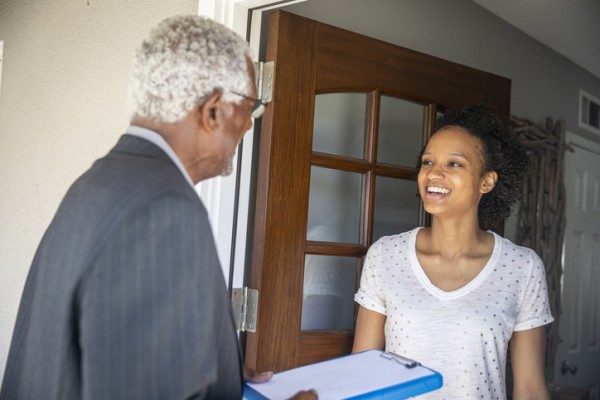 Volunteer at a door with a clipboard and a campaign walk card