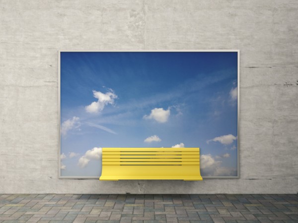 Picture of a bench in front of a blue sky advertisement. 