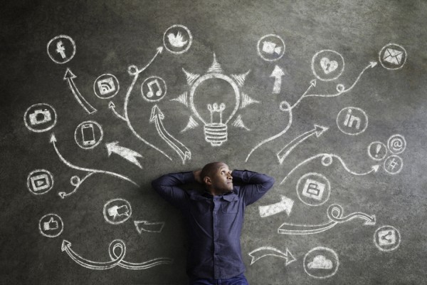 Political Digital Campaign Strategy -Man surrounded by drawings of social media logos on chalkboard in thought bubbles