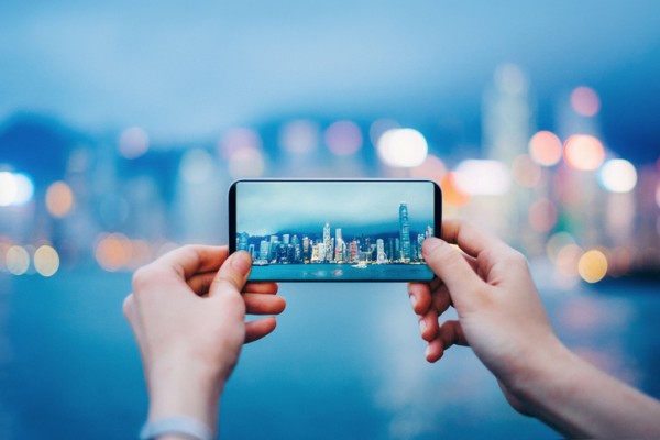 Instagram picture of hands holding up an iPhone taking a picture of a city skyline on the water.