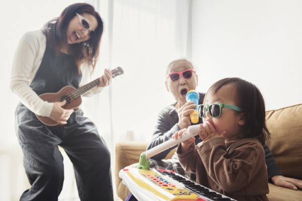 Family singing and playing various instruments in a living room wearing sunglasses. 