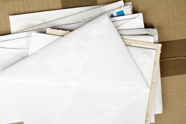 Several pieces of unaddressed mail/envelopes on a cardboard box 