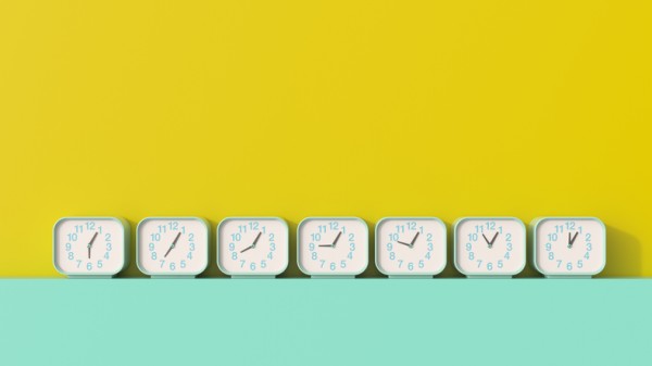 Political direct mail:7 clocks showing different times on a shelf in front of yellow backdrop.