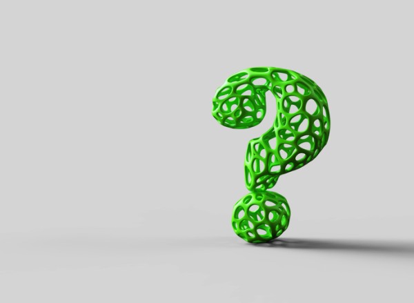 Green question mark made out of rubber with holes on a gray backdrop